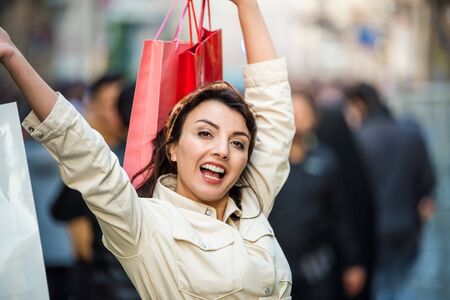 Beautiful attractive young girl in fashionable clothes holds shopping bags after shopping while walking at street. Happy woman with shopping bags.Shopping, lifestyle conceptの写真素材