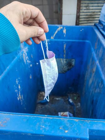 Throwing used face mask to bin or trash. Coronavirus or COVID-19 Concept.throwing medical mask awayの写真素材