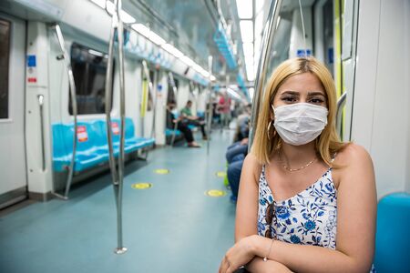 Portrait of happy beautiful woman wearing protective face mask and keeps social distance by sitting alone with smile during covid-19 or coronavirus outbreak .の写真素材