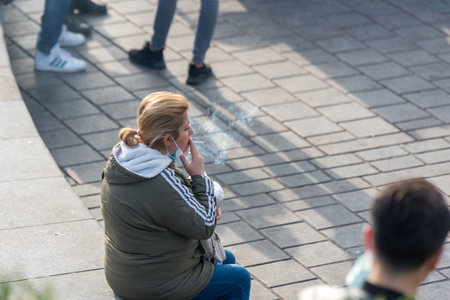 Unidentified Turkish woman wearing half covered protective face masks smokes during coronavirus COVID-19 epidemic.Istanbul,Turkey.16 November 2020のeditorial素材