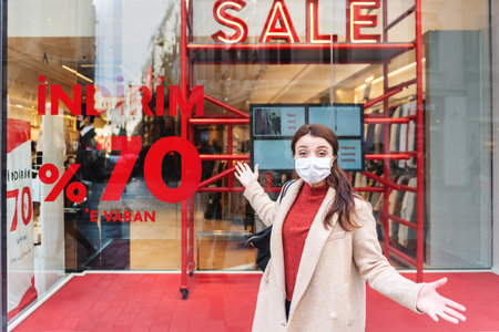 Beautiful girl wearing protective medical mask and fashionable clothes stands in front of...