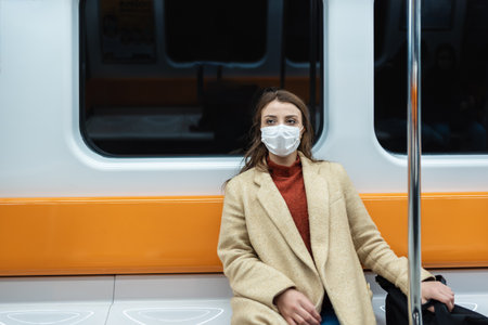 Beautiful woman wearing protective disposable mask keeps social distance by sitting alone while transporting.New normal lifestyle concept.の写真素材
