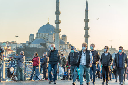 Unidentified Turkish people wearing protective face masks walking at Galata bridge during coronavirus COVID-19 epidemic.Istanbul,Turkey.16 November 2020のeditorial素材
