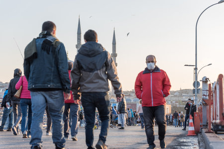 Unidentified Turkish people wearing protective face masks walking at Galata bridge during coronavirus COVID-19 epidemic.Istanbul,Turkey.16 November 2020のeditorial素材