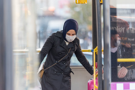 Unidentified Turkish people wearing protective face masks move to get out to buses during coronavirus COVID-19 epidemic.Istanbul,Turkey.16 November 2020のeditorial素材