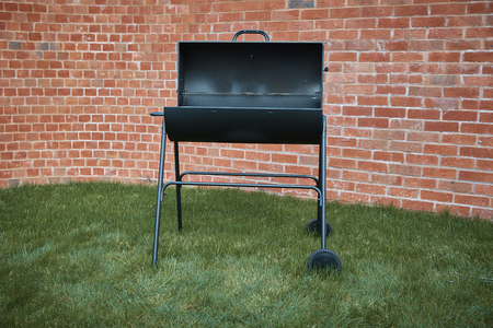 Black big barrel grill in the back garden.