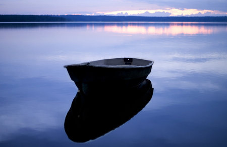 Blue quiet. Moored boat with reflection on the calm water of the lake.の写真素材
