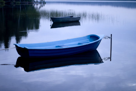 Blue quiet. Moored boat with reflection on the calm water of the lake.の写真素材