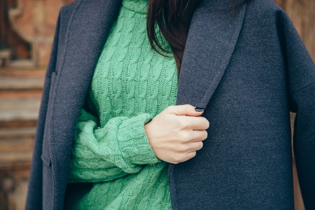 Details of women's clothing. Close-up hand of a woman in a sweater and coat.の写真素材