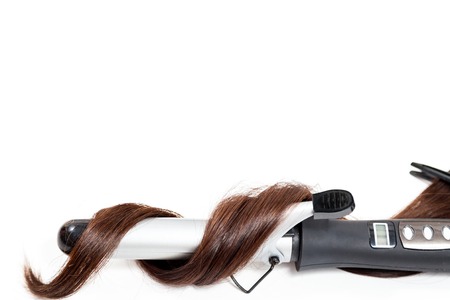 Curly dark hair with a curling iron isolated on white backgroundの写真素材