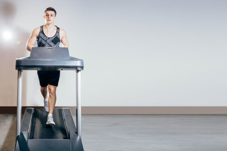 Handsome man doing cardio exercises, running on treadmills in the gym