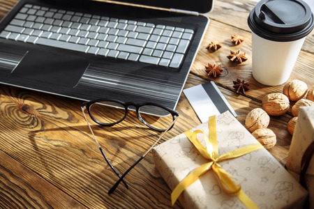 Shopping online with credit card for christmas holiday. Laptop with gifts on wooden table.の写真素材