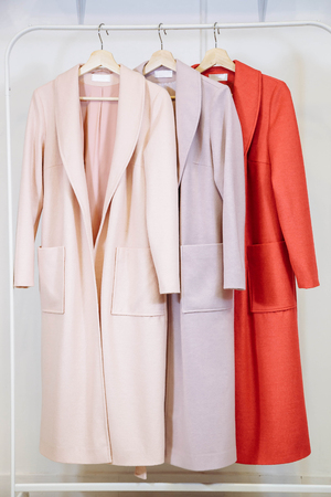 Three women's fashion coats on hangers in the storeの写真素材