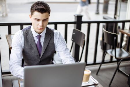Business, technology and people concept - young man with a laptop and coffee cup at city street cafeの写真素材