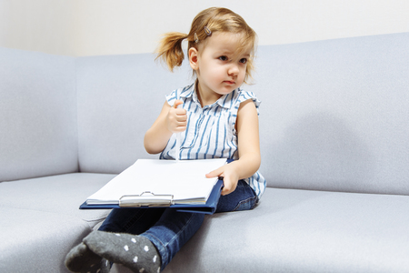 Little girl draws by pen on paper.の写真素材