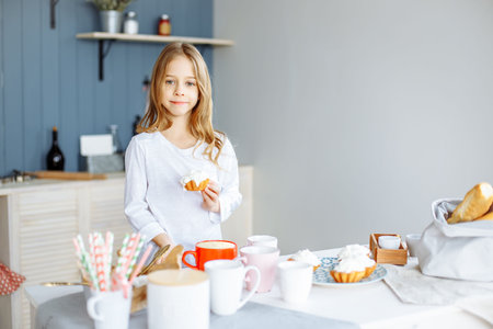 Portrait of cute girl eating sweets in the kitchen.の写真素材