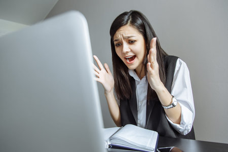 Emotional business lady shouting at her laptop. Hard stressful workday in the office.
