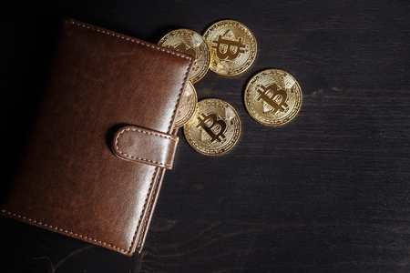 Metal bitcoins in brown leather wallet on dark background. Bitcoin - modern virtualの写真素材