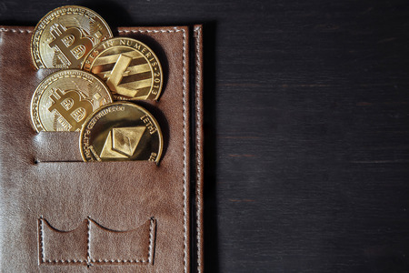Crypto currency coin in leather wallet on dark wooden background. Copy space.の写真素材