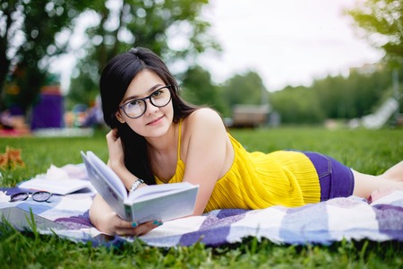 Portrait of a girl reading a book in the parkの写真素材