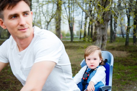 Young father and daughter riding a bicycle in the parkの写真素材