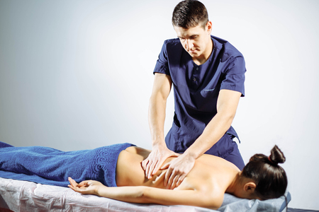 Young male masseur does back massage to the womanの写真素材