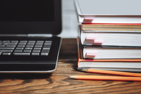 Stack of books and laptop on wooden table.の写真素材