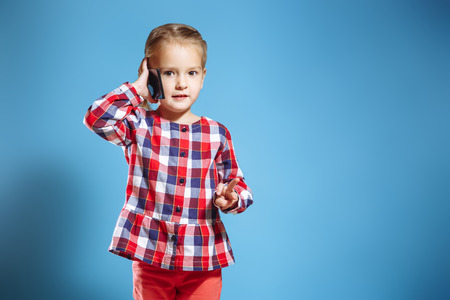 Busy little girl talking on mobile phone on blue background.の写真素材