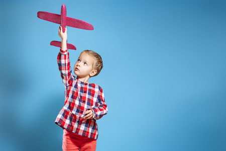 Happy child girl playing with toy airplane. The dream of becoming a pilotの写真素材