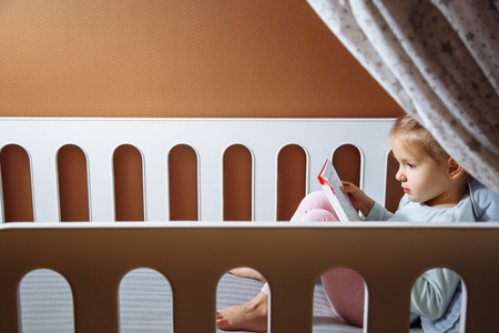 Little girl reading a book in the bedroomの写真素材