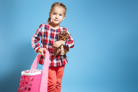 Little girl with a suitcase and a favorite toy on a blue background. Travel concept.の写真素材