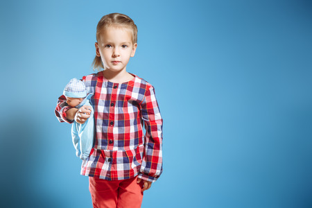 Cute little girl with doll on blue background.の写真素材