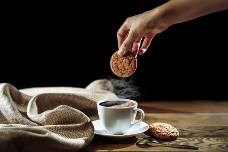 Good morning concept. Breakfast. Female hand holding oatmeal cookies on a dark background.の写真素材