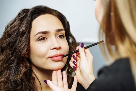 Beautiful model girl applying lipgloss. Lipstick. Professional Make-upの写真素材