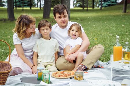 Happy family with kids resting on the grass during a picnic. Happiness and harmony in family lifeの写真素材