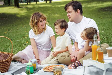 Happy family with kids resting on the grass during a picnic. Happiness and harmony in family lifeの写真素材