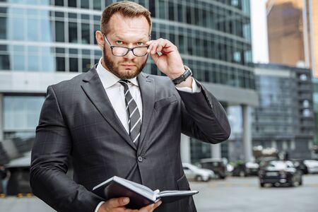 Portrait of a serious business man in a suit and glasses in the cityの写真素材