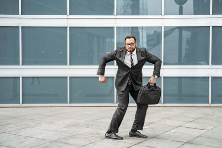 Cheerful business man dancing near the office building on the street.の写真素材