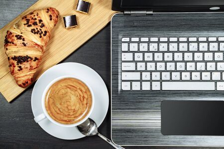 Coffee, croissant and laptop on the table. Breakfastの写真素材