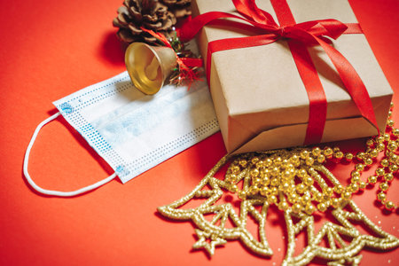 Composition of Christmas decorations, a gift box in a ribbon, fir cones and a protective medical...