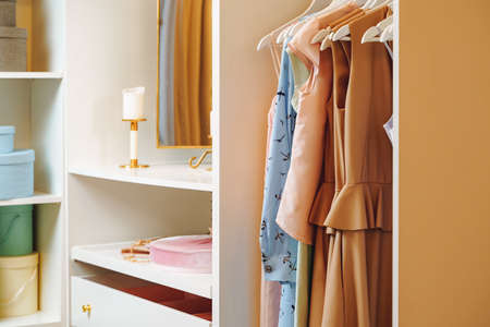 Women's clothing dresses and blouses on hangers in a dressing room or store.の写真素材