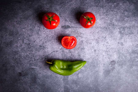 three tomatoes and a pepper forming a faceの写真素材