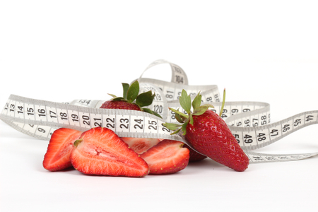 big juicy red ripe strawberries and measure tape isolated on whiteの写真素材