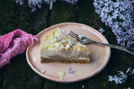 homemade cheesecake and lilac flowers on a wooden table