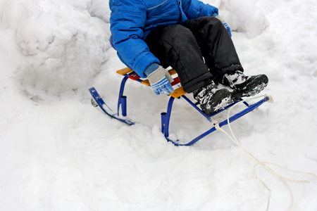 Walking outdoors in the winter time. The child is sitting in a sled through deep snow.の写真素材