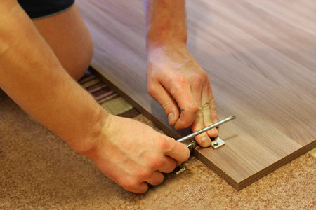 Assembling furniture. The image of a man who by means of a screwdriver engaged in the Assembly of...