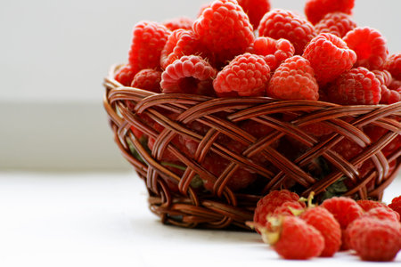 Berry background.Berries red ripe raspberries folded into a small wicker basket. A few raspberries...