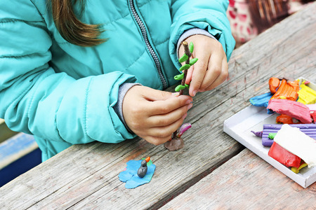 Child to play outdoors. The image is part of small child playing with plasticine in the street behind the mahogany Desk. A child plays with clay and various natural materials with different shapes.の写真素材