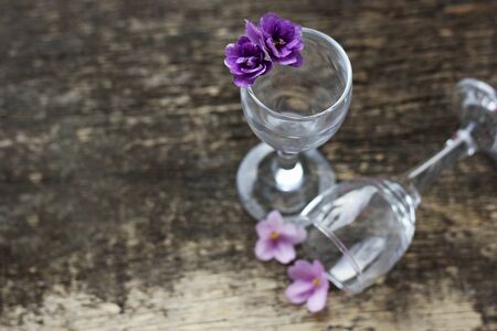 The flowers are violets. Floral background.The flower in the glass. A few small violet flowers in a transparent glass glasses.Glasses on the wooden surface.の写真素材