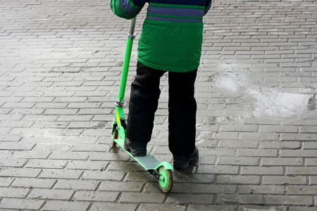 Walking the baby in the fresh air. Boy riding in the cold season on the scooter on the paths of the Park.の写真素材